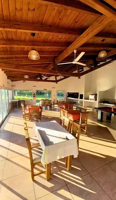 a large room with tables and chairs and a piano at Cabañas El Principio in Villa Cura Brochero