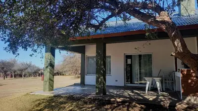 a house with a table and chairs in a yard at Cabañas El Principio in Villa Cura Brochero