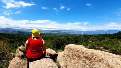 a woman sitting on top of a rock on a hill at Cabañas El Principio in Villa Cura Brochero