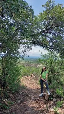 a woman sitting on a trail under a tree at Cabañas El Principio in Villa Cura Brochero