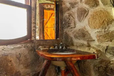 a stone bathroom with a wooden sink and a window at Habitaciones individuales en La Llave in San Javier