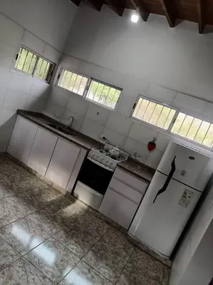 an empty kitchen with white appliances and windows at Cabañas Los Ranqueles in Merlo