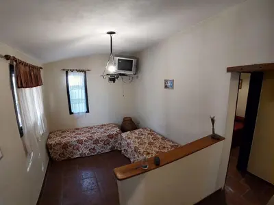 a small room with a bed and a tv on the wall at CABAÑA Aguadita Tanti in Tanti