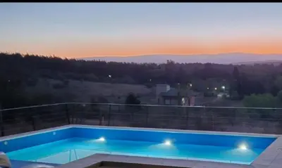 a swimming pool on a balcony with a sunset in the background at Chalet REMANSO DE PAZ in Los Reartes