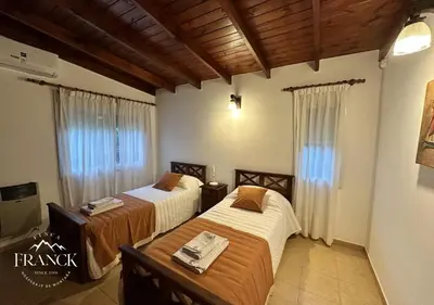 two beds in a room with wooden ceilings at FINCA FRANCK - Hospedaje de Montaña in Los Reartes