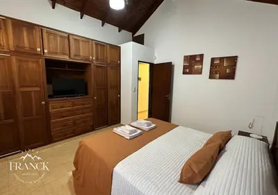 a bedroom with a bed and a tv and cabinets at FINCA FRANCK - Hospedaje de Montaña in Los Reartes