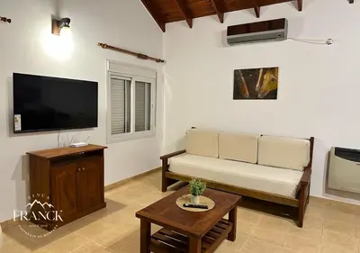 a living room with a couch and a flat screen tv at FINCA FRANCK - Hospedaje de Montaña in Los Reartes
