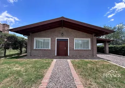 a small brick house with a red door at FINCA FRANCK - Hospedaje de Montaña in Los Reartes
