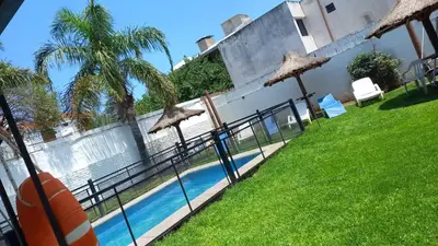 a swimming pool with umbrellas in front of a building at Complejo Luluara in Villa Carlos Paz