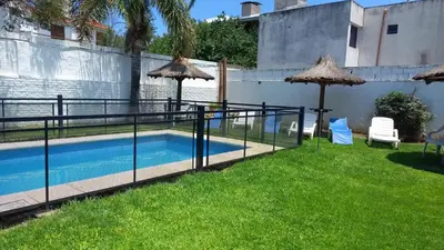 a pool with umbrellas next to a yard at Complejo Luluara in Villa Carlos Paz