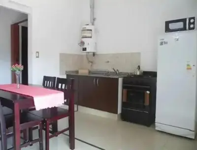 a kitchen with a table and a white refrigerator at Complejo Luluara in Villa Carlos Paz