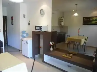a living room with a kitchen and a table with a microwave at Complejo Luluara in Villa Carlos Paz