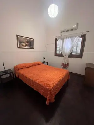 a bedroom with a bed with an orange comforter and a window at Departamento Peña in Villa Carlos Paz
