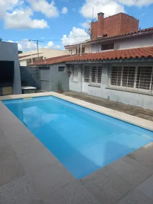a large blue swimming pool in front of a house at Departamento Peña in Villa Carlos Paz