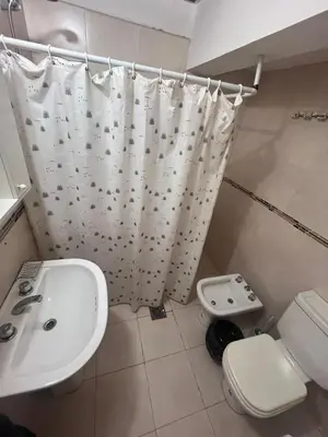 a bathroom with a sink and a toilet and a shower curtain at Departamento Peña in Villa Carlos Paz