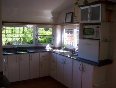 a kitchen with white cabinets and a sink and a microwave at Casa Chaco in Villa Carlos Paz