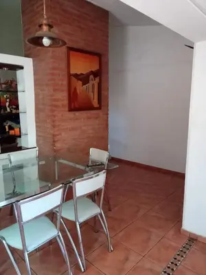 a dining room with a glass table and white chairs at Casa Chaco in Villa Carlos Paz