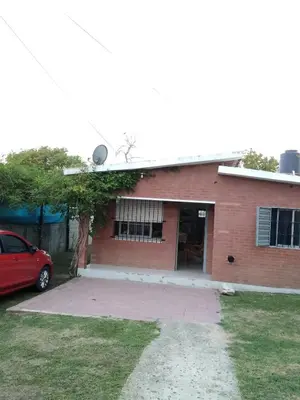a red brick house with a red car parked in front at La Mericia in Villa Carlos Paz