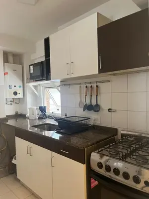 a kitchen with white cabinets and a stove top oven at Raiz - Alquileres Temporarios in Cordoba