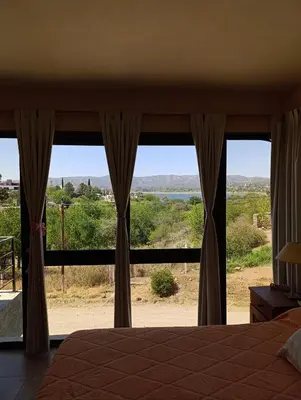 a bedroom with a large window with a view at Complejo Refugio Playa Perelli in Villa Carlos Paz
