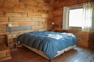 a bedroom with a bed in a log cabin at Cabañas del Peñón in La Cumbrecita