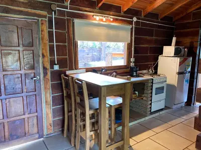 a kitchen with a table and a stove and a refrigerator at Cabañas del Peñón in La Cumbrecita