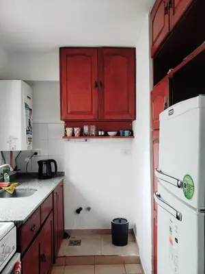 a kitchen with red cabinets and a white refrigerator at Departamento en Barrio Centro calle Corro in Cordoba