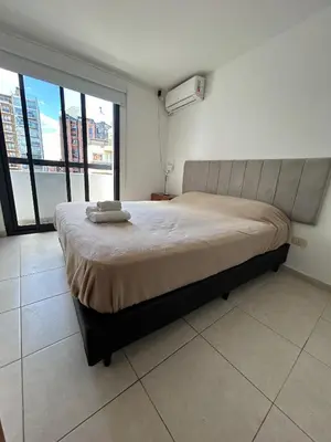 a bedroom with a large bed with a large window at Departamento -Santo Tomas- Barrio Guemes-Nueva Cordoba By Apartcba in Cordoba