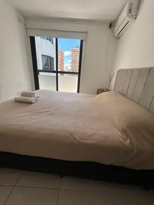 a large bed in a room with a large window at Departamento -Santo Tomas- Barrio Guemes-Nueva Cordoba By Apartcba in Cordoba