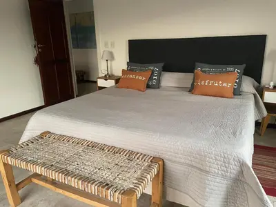 a bedroom with a large bed with a bench on it at Casa en Potrerillo de Larreta Magicas Vistas in Alta Gracia