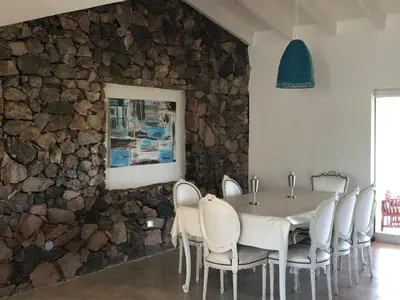a dining room with a table and chairs and a stone wall at Casa en Potrerillo de Larreta Magicas Vistas in Alta Gracia