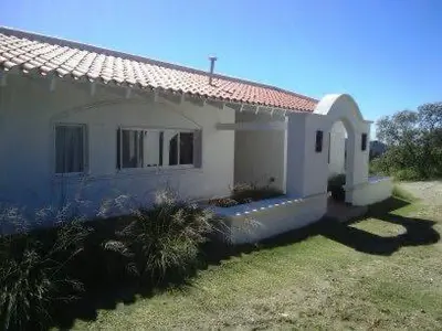 a small white house with a grass yard at Casa en Potrerillo de Larreta Magicas Vistas in Alta Gracia