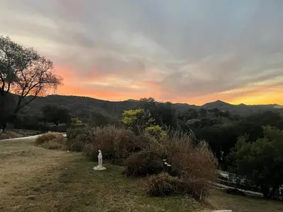 a statue on a hill with a sunset in the background at Casa en Potrerillo de Larreta Magicas Vistas in Alta Gracia