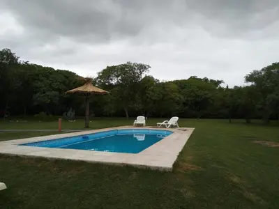 a swimming pool with two chairs and an umbrella at chalet la granadilla in Cerro de Oro