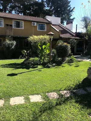 a house with a lawn in front of it at cabañas el viejo ciprés 1 in Santa Rosa de Calamuchita