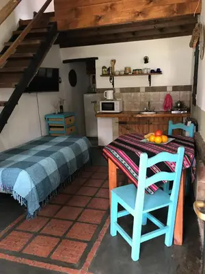 a kitchen with a table and a bed in a room at cabañas el viejo ciprés 1 in Santa Rosa de Calamuchita
