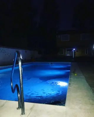 a swimming pool at night with a light in the water at cabañas el viejo ciprés 1 in Santa Rosa de Calamuchita