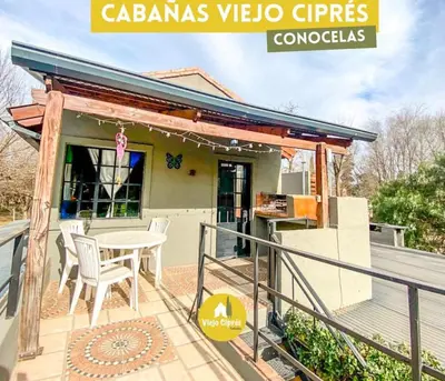 a patio with a table and chairs on a deck at cabañas el viejo ciprés 1 in Santa Rosa de Calamuchita