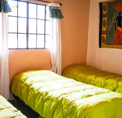 two beds sitting in a room with a window at cabañas el viejo ciprés 2 in Santa Rosa de Calamuchita
