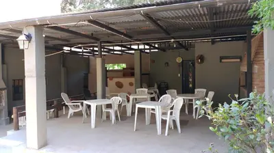 a patio with white tables and chairs under a pergola at cabañas el viejo ciprés 2 in Santa Rosa de Calamuchita