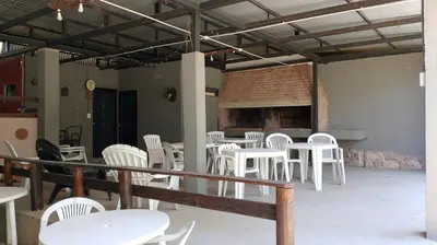 a room with white chairs and tables and a fireplace at cabañas el viejo ciprés 2 in Santa Rosa de Calamuchita