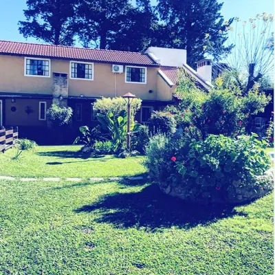 a house with a garden in front of it at cabañas el viejo ciprés 3 in Santa Rosa de Calamuchita
