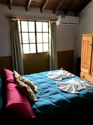 a bedroom with a blue bed with a window at cabañas el viejo ciprés 3 in Santa Rosa de Calamuchita