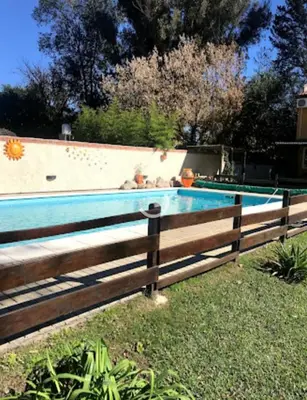 a swimming pool with a wooden fence around it at cabañas el viejo ciprés 3 in Santa Rosa de Calamuchita
