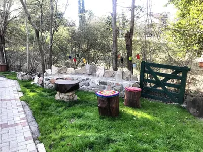 a garden with a stone wall and two stump stools at cabañas el viejo ciprés 3 in Santa Rosa de Calamuchita