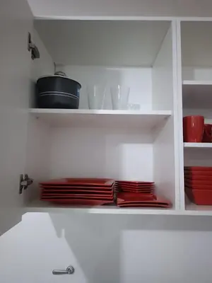 a white cabinet with red plates and dishes on it at Dpto amoblado in Cordoba