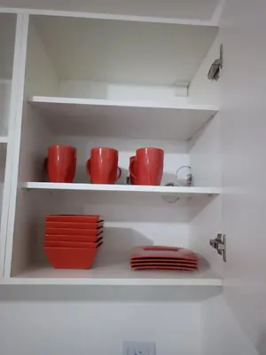 a shelf with red cups and plates on it at Dpto amoblado in Cordoba