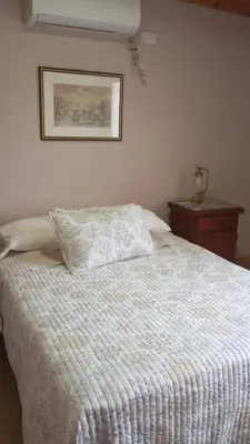a bed with a white blanket and a picture on the wall at Dpto amueblado con cochera descubierta in Río Tercero