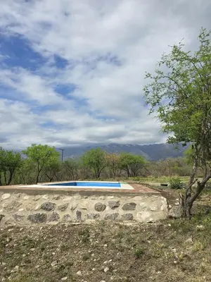 a swimming pool in a field with a tree at El Alto in Yacanto
