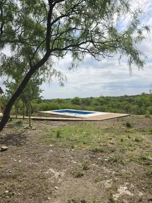 a swimming pool in a field with a tree at El Alto in Yacanto